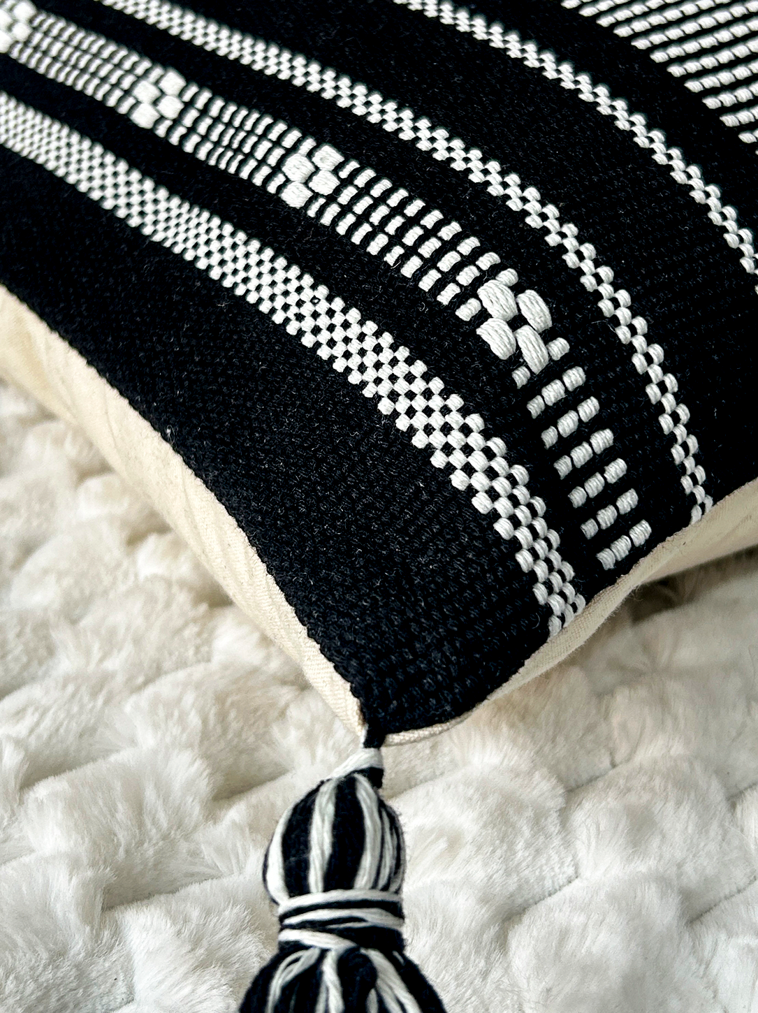Cojín Étnico Noir de La Mía Stanza sobre sofá beige con diseño geométrico en blanco y negro.