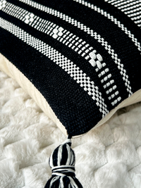 Cojín Étnico Noir de La Mía Stanza sobre sofá beige con diseño geométrico en blanco y negro.